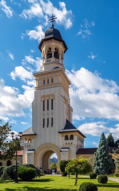 Alba Iulia, Romanya - Ekim 19.2025. Taç giyme töreninin büyük çan kulesi Alba Carolina Kalesi 'nde beyaz bulutlu açık mavi bir gökyüzüne karşı duruyor.