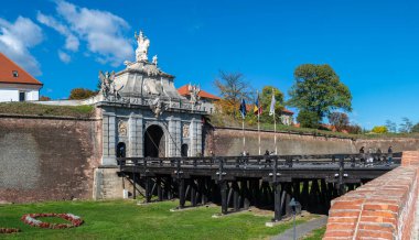 Alba Iulia, Romanya - Ekim 19.2025. Romanya 'daki Alba Carolina Kalesi' ndeki tarihi ahşap köprünün sonunda heykeli olan süslü bir barok taş kapı duruyor.