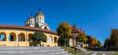 Alba Iulia, Romanya - Ekim 19.2025. Taç giyme töreninin büyük çan kulesi, Romanya 'nın Alba Iulia kentindeki Prenslik Sarayı' nın tarihi beyaz cephesinin hemen yanında yer alıyor.