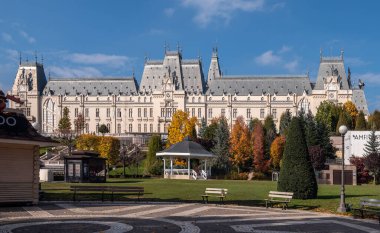 Iasi, Romanya - 23 Ekim 2025. Romanya 'da güneşli bir günde modern binalar ve renkli sonbahar ağaçlarıyla dolu Palas Iasi bahçesi