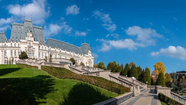 Iasi, Romanya - 23 Ekim 2025. Iasi Romanya 'daki Neo-Gotik Kültür Sarayı' nın geniş panoramik manzarasında, parlak mavi gökyüzü altında fıskiyeler ve sonbahar ağaçları bulunan bereketli Palas Halk Bahçesi yer alıyor.