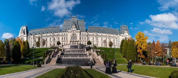 Iasi, Romanya - 23 Ekim 2025. Iasi Romanya 'daki Neo-Gotik Kültür Sarayı' nın geniş panoramik manzarasında, parlak mavi gökyüzü altında fıskiyeler ve sonbahar ağaçları bulunan bereketli Palas Halk Bahçesi yer alıyor.