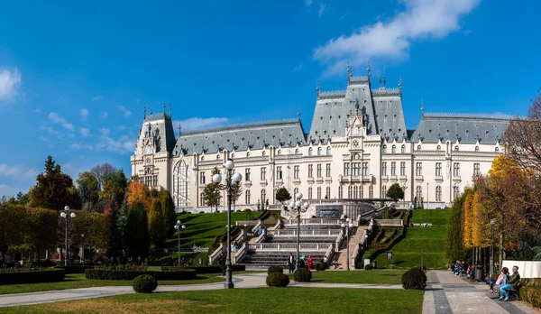 Iasi, Romanya - 23 Ekim 2025. Iasi Romanya 'daki Neo-Gotik Kültür Sarayı' nın geniş panoramik manzarasında, parlak mavi gökyüzü altında fıskiyeler ve sonbahar ağaçları bulunan bereketli Palas Halk Bahçesi yer alıyor.