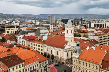 Cluj-Napoca, Romanya - Ekim 18.2025 Romanya 'nın Cluj-Napoca kentinin tarihi merkezi, bulutlu bir gökyüzü altında geleneksel kırmızı başlıklı çatılar, şehir sokakları ve St. Michael Kilisesi' ni gösteriyor.