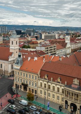 Cluj-Napoca, Romanya - Ekim 18.2025 Romanya 'nın Cluj-Napoca kentinin tarihi merkezi, bulutlu bir gökyüzü altında geleneksel kırmızı başlıklı çatılar, şehir sokakları ve St. Michael Kilisesi' ni gösteriyor.