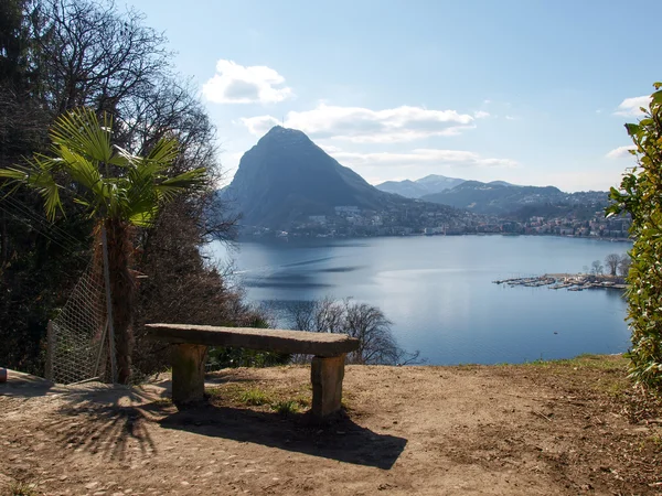 Marmor bänk med utsikt över viken i Lugano och montera San Fraguas — Stockfoto