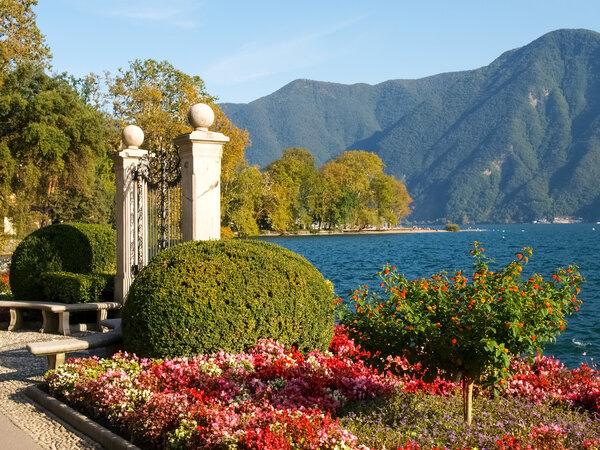Lugano, Switzerland: Park of the City. Picture from the botanical park by the lake and surrounding mountains with flowers
