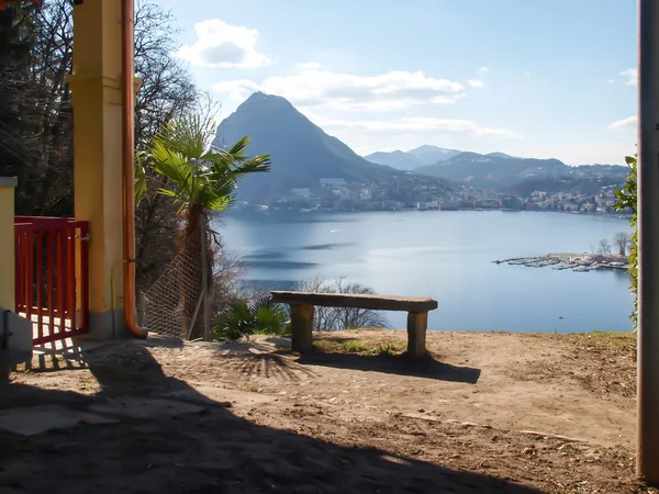 Mramorové lavičce s výhledem na záliv Lugano a hora San Salvat — Stock fotografie