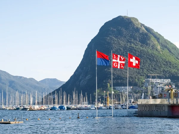 Lago Lugano, Monte San Salvatore y las banderas de Suiza , — Foto de Stock