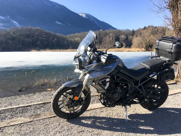 Carlazzo, İtalya 7 Temmuz 2019: Park etmiş bir motosikletle yarı donmuş Piyano Gölü.