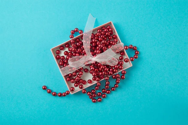Рожева подарункова коробка з червоним бісером на синьому фоні. — стокове фото