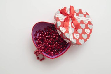Beyaz arka planda kırmızı boncukları olan kalp şeklinde bir hediye kutusu. Sevgililer Günü. Anneler Günü. Kadınlar Günü