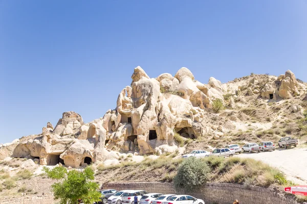 CAPPADOCIA, TURKEY - JUN 25, 2014: Photo of car parking on the background of cliffs with caves at the Goreme National Park — Stock Photo, Image