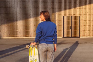 Şehir merkezinde kaykaylı bir kadın. Kadın kaykaycı mavi kazak giyer..