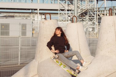 Siyah kapüşonlu genç esmer kadın dalgaların üzerinde oturuyor..