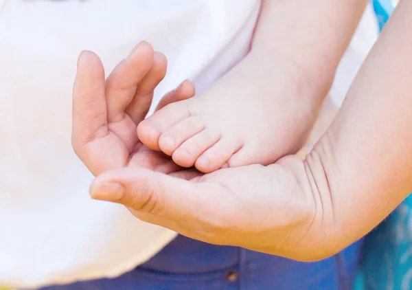 Bebé pies en la mano madre — Foto de Stock