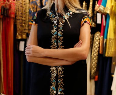 Kadın göğsünü kapat ve ellerini çapraz yap geleneksel Hint nakışlı kurti yeleği giyerek giyim mağazasının arka planında 