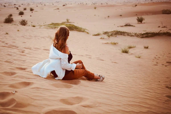 女性はアラブ首長国連邦ドバイのサファリ中に砂漠の砂丘に座っています — ストック写真
