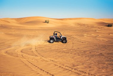 Dubai, BAE - 12.13.2014: Böcek dörtlü bisiklet sürüşü ve çöl kumunda sürükleniş, iz ve toz, çok uzakta ekstrem sporlar 