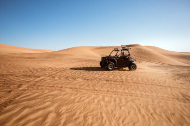 Dubai, BAE - 12.13.2014: Kasklı kadın sürücü safari kum tepelerinde emirlik bayraklarıyla siyah dört çeker bisiklet, açık hava eğlencesi