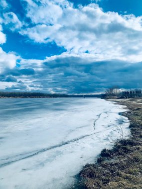 Buz ve kar ve dramatik bulutlu gökyüzü ile Donmuş Dinyeper Nehri yüzeyi ile soğuk kış manzarası
