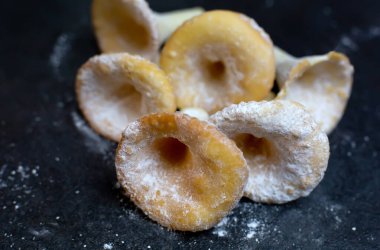 Bisküvileri kapat, şeker tozlu kurabiyeler mantar şeklinde, garip şekilli tatlı yiyecekler karanlık masa arkasında.