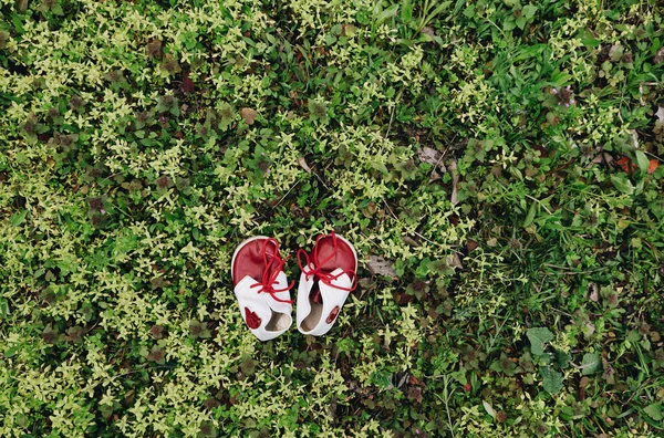 皮革婴儿复古白色和红色靴子 鞋带在绿草之上 顶部视图 第一个婴儿幼儿鞋 — 图库照片