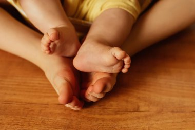Farklı yaşlarda iki kız kardeş, tahta zeminde yalın ayak, küçük ayak parmakları, aile sevgisi kavramı.