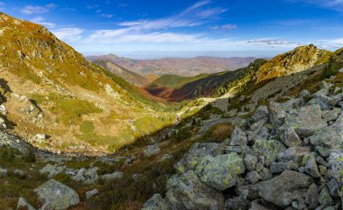 Yüksek Scardus patikasından (ar Planina) görülen katmanlı bir dağ manzarası, ışık ve canlı sonbahar renkleriyle aydınlatılır..