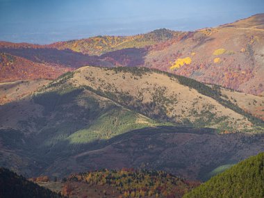 Yüksek Scardus patikasından (ar Planina) görülen katmanlı bir dağ manzarası, ışık ve canlı sonbahar renkleriyle aydınlatılır..
