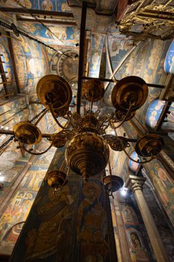 DEAN, KOSOVO OCTOBER 26, 2025: Visoki Deani Manastırı 'nın içinde freskli, kubbeli tavanın altında asılı büyük pirinç avizenin (policandelon) yakın görüntüsü.