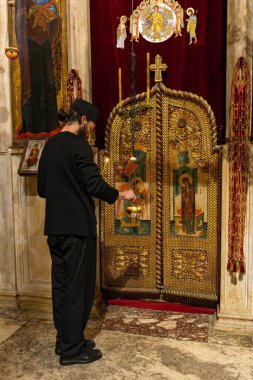 DEAN, KOSOVO OCTOBER 26, 2025: Visoki Deani Manastırı 'ndaki zengin yaldızlı ikonostaz' da mum yakan veya bir ikona tapan Sırp Ortodoks keşişi