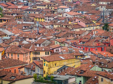 Brescia 'nın tarihi merkezinin, karakteristik kırmızı ve turuncu terasotta kiremitli çatıları olan geleneksel binaların yoğun ve renkli düzenini vurgulayan yüksek ve yakın bir görüntüsü.