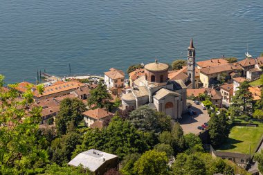 Laveno Mombello 'nun yüksek manzarası, kendine özgü kubbesi ve bitişik çan kulesiyle Sant' Ambrogio Kilisesi 'ni sergiliyor. Maggiore Gölü ve çevresindeki tepelere karşı kurulmuş.