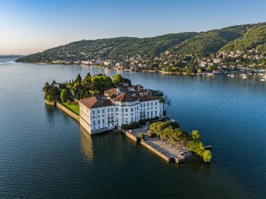 Isola Bella 'da bulunan ve Maggiore Gölü' nün koyu mavi suları ve anakaranın yeşil kaplı tepeleriyle çevrili çarpıcı beyaz Borromeo Sarayı 'nın (Palazzo Borromeo Sarayı) hava manzarası.