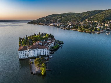 Isola Bella 'da bulunan ve Maggiore Gölü' nün koyu mavi suları ve anakaranın yeşil kaplı tepeleriyle çevrili çarpıcı beyaz Borromeo Sarayı 'nın (Palazzo Borromeo Sarayı) hava manzarası.