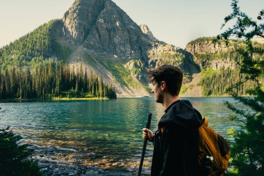 Hiker admiring mountain lake scenery, exploring the great outdoors solo.