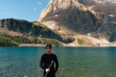 Lake and mountain landscape with person holding a hiking stick for stability.