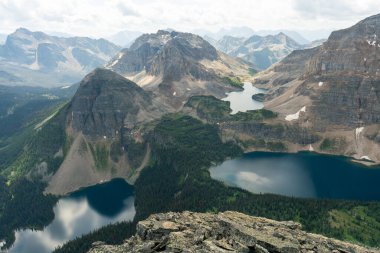Mountain peaks frame a scenic lake landscape under a cloudy sky.