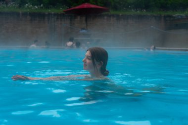 Kaplıcada dinlenen bir kadın, rahatlatıcı suyun tadını çıkarıyor. Radyum Kaplıcaları, BC