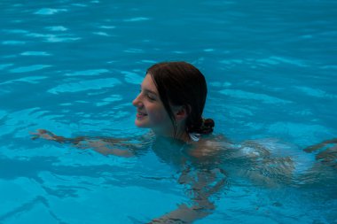 Bir kız açık, masmavi bir yüzme havuzunda ferahlatıcı bir yüzüşten hoşlanır. Radyum Kaplıcaları, BC