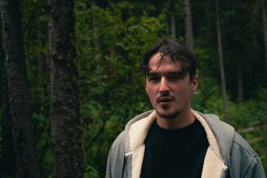 Adam ormanda doğal ortamlarda günlük giysiler giyerek duruyor. Radyum Kaplıcaları, BC