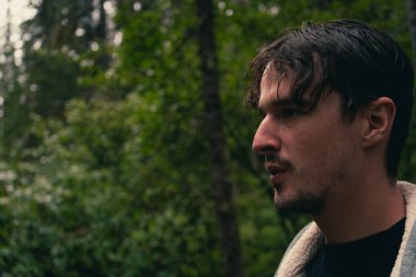 Dalgın adam ormana bakıyor, karamsar ve doğal bir ortamın arka planı. Radyum Kaplıcaları, BC