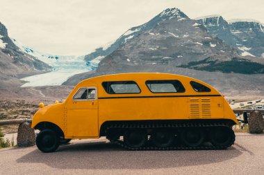 Arkasında karlı dağlar olan sarı buz kaşifi. Keşif aracı. Columbia Buz Sahası, AB