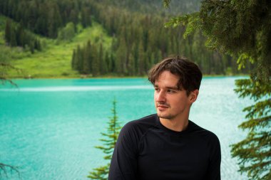 Odaklanmış adam yemyeşil yemyeşil tarafından kucaklanan canlı turkuaz göle bakıyor. Zümrüt Gölü, BC