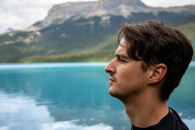 Şahıs heybetli dağ manzaralarıyla çevrili sakin gölü düşünüyor. Zümrüt Gölü, BC