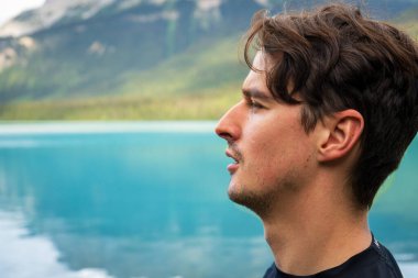 Göle bakan bir adamın profili, ufuktaki dağların profili. Zümrüt Gölü, BC