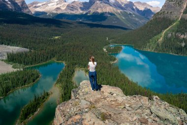 Göl ve ağaçlarla manzaralı dağ manzarası. Doğanın tadını çıkaran bir kadın. OHara Gölü, BC