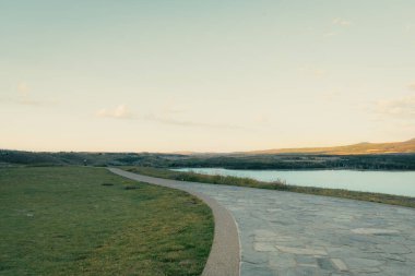 Etrafı uzak yamaçlarla çevrili sakin bir göle açılan dolambaçlı bir yol. Waterton, AB