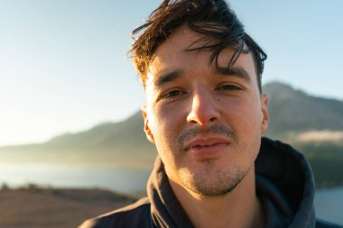 Güneş doğarken adam yakın plan çekimde. Arka plandaki dağ ve göl bulanık. Waterton, AB